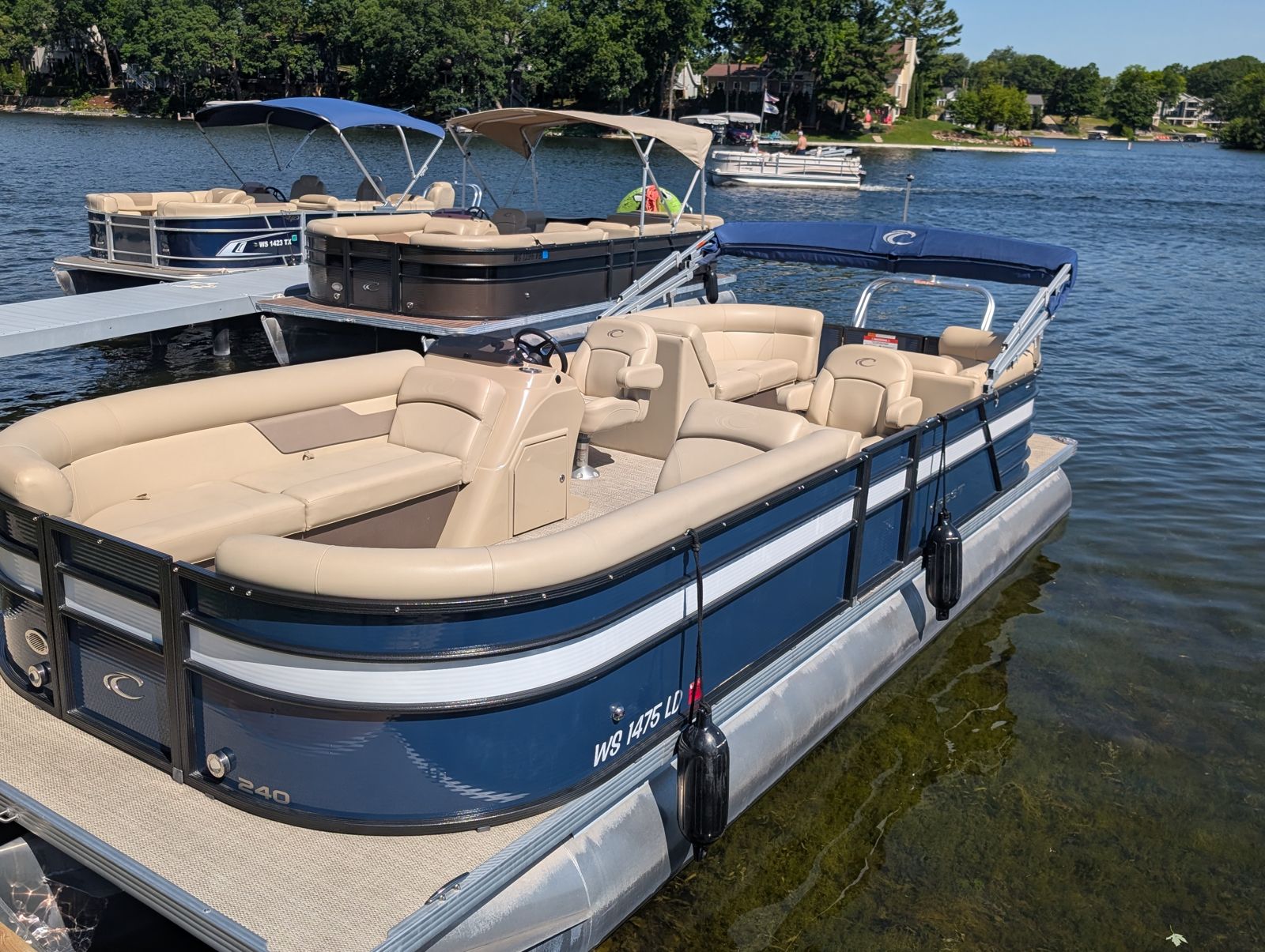 A navy and cream Golden Boat pontoon tied up at the dock on a clear day