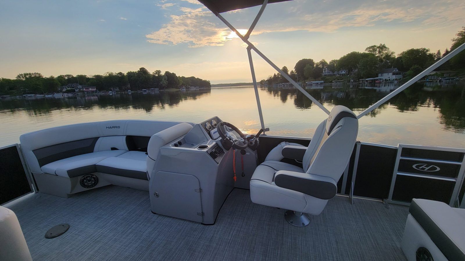 View from a pontoon deck across a calm Okauchee Lake at golden hour