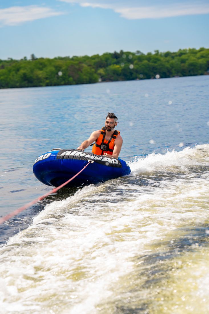 A rider on a tube skipping across the wake behind a pontoon